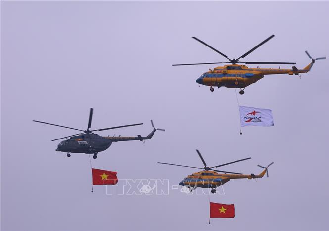 Biên đội trực thăng dòng Mi thuộc Trung đoàn không quân 916 cùng cờ Tổ quốc và cờ hiệu Triển lãm Quân sự quốc tế Việt Nam 2022 biểu diễn trên không gian triển lãm. Ảnh: Văn Điệp - TTXVN