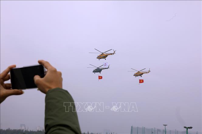 Biên đội trực thăng dòng Mi thuộc Trung đoàn không quân 916 cùng cờ Tổ quốc và cờ hiệu Triển lãm Quân sự quốc tế Việt Nam 2022 biểu diễn trên không gian triển lãm. Ảnh: Văn Điệp - TTXVN