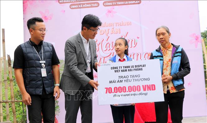 Ông Park Young Dall, Giám đốc khối Hành chính nhân sự LG Display trao tặng hai mẹ con em Nguyễn Thị Hiền tiền xây nhà mới. Ảnh: Minh Thu - TTXVN