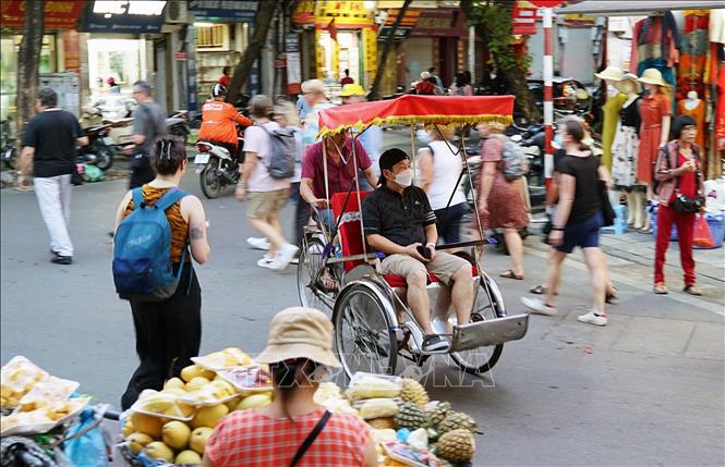 Du khách trải nghiệm tham quan đường phố Hà Nội bằng xích lô trên tuyến phố Hàng Bạc. Ảnh: Khánh Hòa - TTXVN 