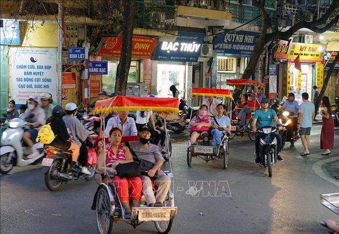 Du khách trải nghiệm tham quan khu phố cổ, ngắm cảnh bằng xích lô trên phố Đinh Liệt. Ảnh: Khánh Hòa - TTXVN 