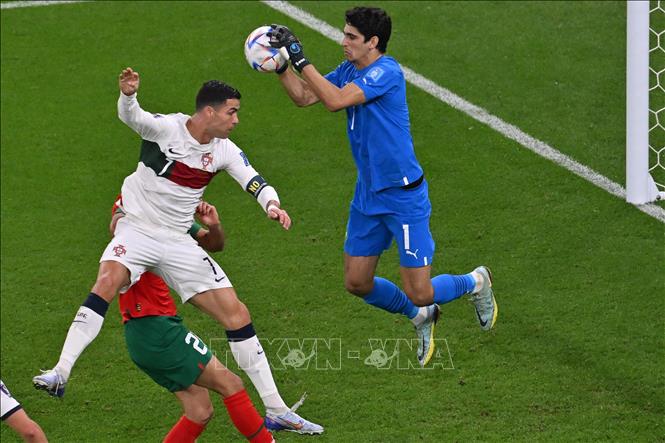 Bruno Fernandes chuyền bóng vào vòng cấm cho Cristiano Ronaldo (trái), nhưng tiền đạo Bồ Đào Nha không thể tung ra cú đánh đầu vì sự can thiệp của thủ môn Maroc Yassine Bounou (phải). Ảnh: AFP/ TTXVN