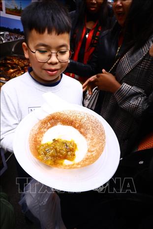 A kid enjoys a dish from Mozambique. VNA Photo: Lâm Khánh
