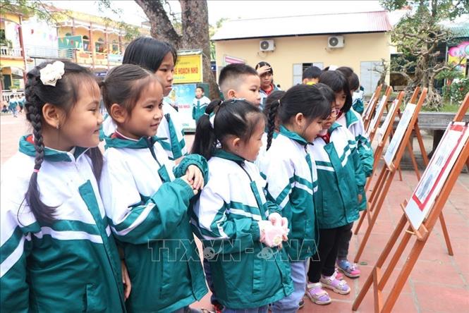 Trong ảnh: Các em học sinh trường Tiểu học Cẩm Điền xem trưng bày tranh vẽ và các bài thi viết chữ đẹp về di tích Văn Miếu Mao Điền. Ảnh: Mạnh Minh - TTXVN