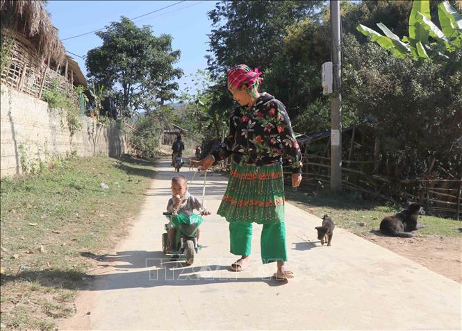 Trong ảnh: Hai bà cháu người dân tộc Mông tại bản Na Côm (xã Hẹ Muông, huyện Điện Biên, tỉnh Điện Biên) dạo chơi trên con đường liên bản. Ảnh: Xuân Tiến – TTXVN 