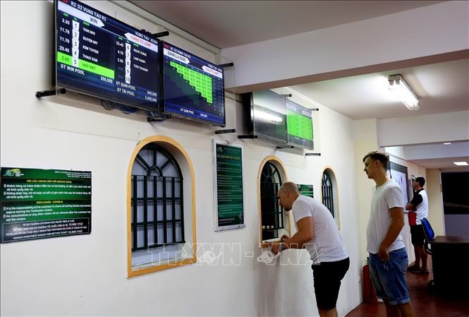 Foreign tourists buy bet tickets at Greyhound dog racecourse in the coastal city of Vung Tau. VNA Photo: Hồng Đạt