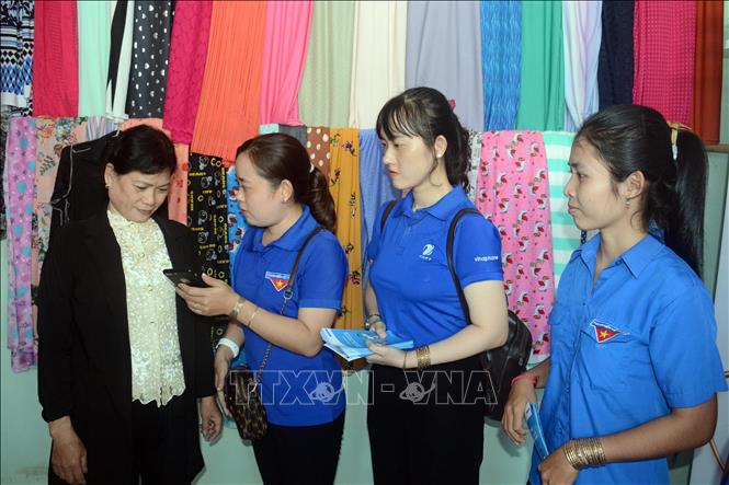 Đoàn viên, thanh niên huyện Trần Đề ( tỉnh Sóc Trăng) hướng dẫn người dân áp dụng thanh toán thông qua mã QR từ phần mềm Viettel money và VNPT money. Ảnh: Tuấn Phi - TTXVN