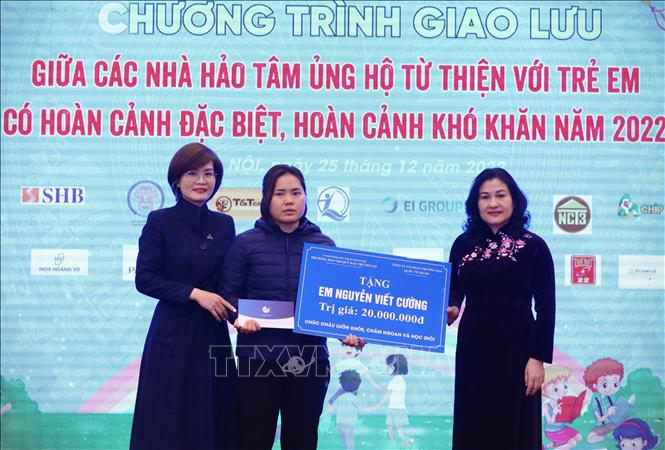 Thứ trưởng Bộ Lao động - Thương binh và Xã hội Nguyễn Thị Hà (phải) và Phó Giám đốc Công ty Cổ phần thương mại quốc tế Pacos Hà Thị Nghi trao hỗ trợ 20 triệu đồng cho mẹ em Nguyễn Viết Cường bị bệnh hiểm nghèo. Ảnh: Hoàng Hiếu - TTXVN 