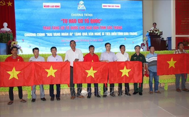 Đại diện lãnh đạo các sở, ngành tỉnh Sóc Trăng, Báo Người Lao Động và UBND huyện Trần Đề trao tặng cờ Tổ quốc cho ngư dân. Ảnh: Nhật Bình - TTXVN
