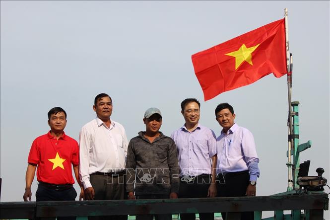 Đại diện lãnh đạo các sở, ngành tỉnh Sóc Trăng, Báo Người Lao Động và UBND huyện Trần Đề trao tặng cờ Tổ quốc cho ngư dân. Ảnh: Nhật Bình - TTXVN