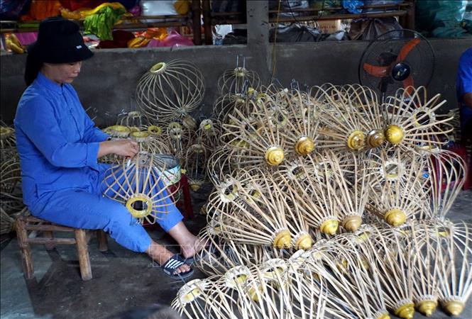 Các nghệ nhân thực hiện các công đoạn trong sản xuất đèn lồng ở thành phố Hội An. Ảnh: Trịnh Bang Nhiệm - TTXVN