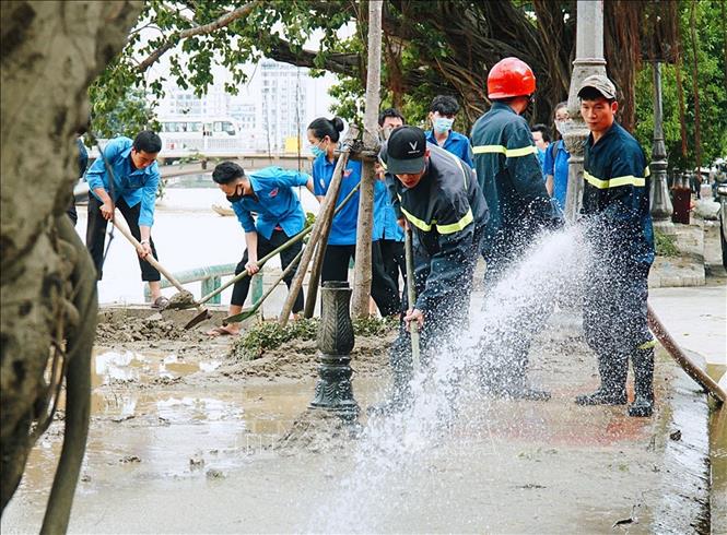 Lực lượng đoàn viên thanh niên Thừa Thiên - Huế tham gia dọn vệ sinh đường phố khắc phục hậu quả sau lũ lụt. Ảnh: TTXVN phát