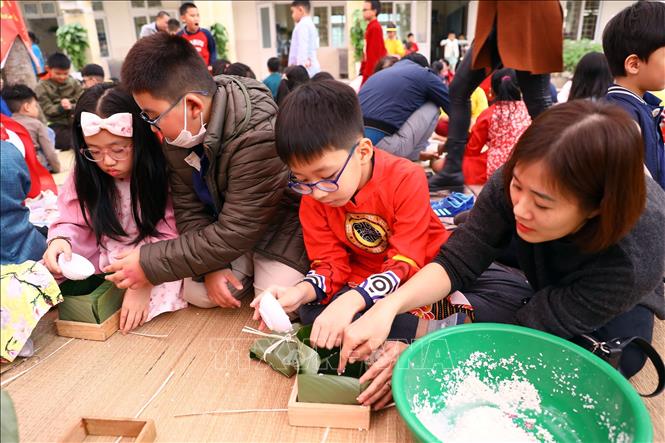 Các phụ huynh và học sinh tham gia gói bánh chưng Tết. Ảnh: Huy Hùng - TTXVN
