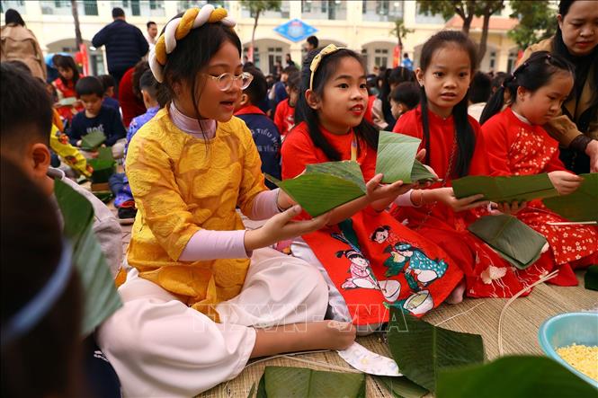 Các em nhỏ rất hào hứng khi được tự tay gói cho mình bánh chưng đón Tết. Ảnh: Huy Hùng - TTXVN