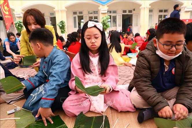 Các bạn nhỏ tham gia gói bánh chưng ngày Tết. Ảnh: Huy Hùng - TTXVN