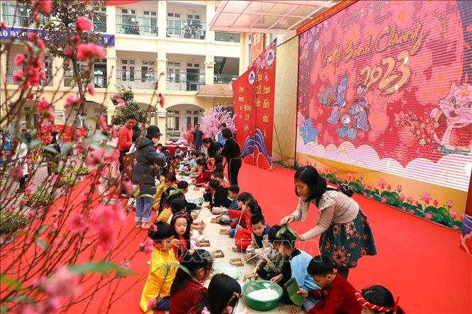 Các em học sinh tham gia gói bánh chưng. Ảnh: Huy Hùng - TTXVN