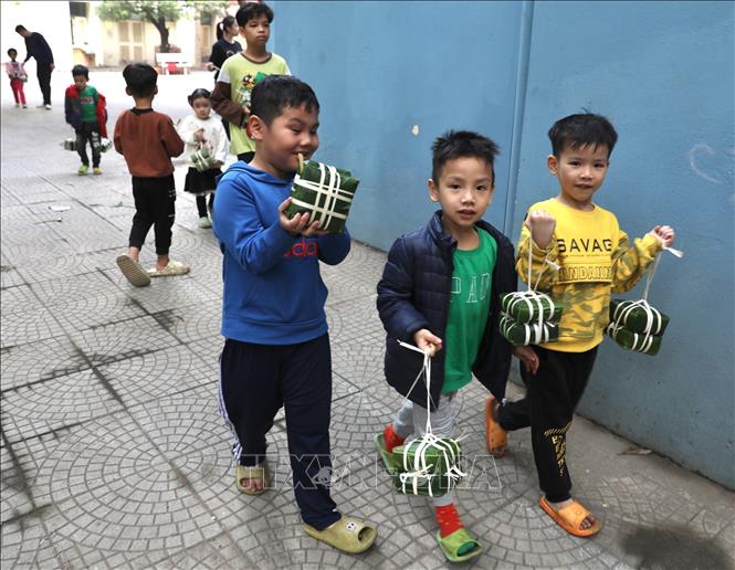 Các em thích thú với trải nghiệm chuẩn bị luộc bánh chưng. Ảnh: Hoàng Hiếu - TTXVN 