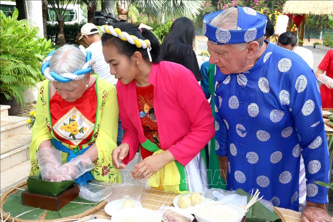 Foreign tourists experience the Vietnamese traditional Tet atmosphere through making banh chung (glutinous rice cake typical during Tet festival). VNA Photo: Nguyễn Thành