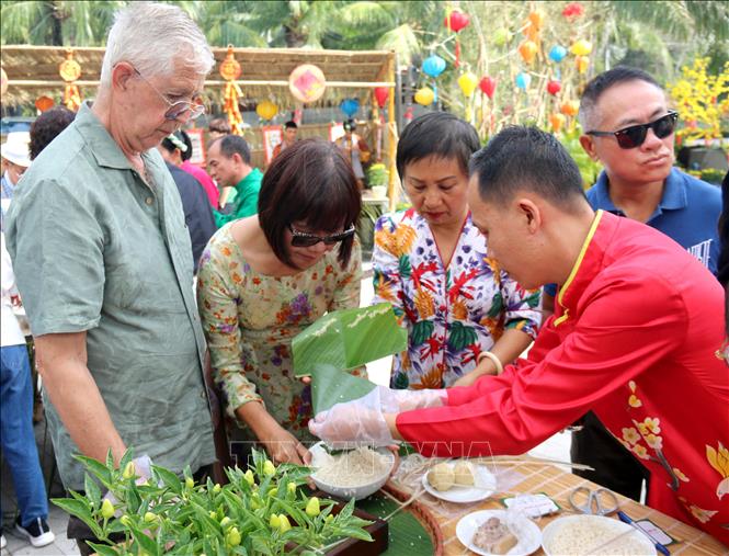 Foreign tourists experience the Vietnamese traditional Tet atmosphere through making banh chung (glutinous rice cake typical during Tet festival). VNA Photo: Nguyễn Thành