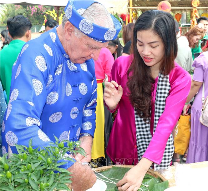 Foreign tourists experience the Vietnamese traditional Tet atmosphere through making banh chung (glutinous rice cake typical during Tet festival). VNA Photo: Nguyễn Thành