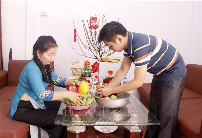 Trong ảnh: Bà Cương và con trai đang cùng nhau bày mâm ngũ quả  để chuẩn bị đón Tết.  Ảnh: Bá Thành - Phóng viên TTXVN tại Lào.