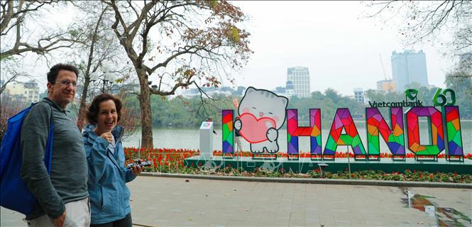 Khách quốc tế tản bộ ngắm cảnh hồ Gươm trong tiết Xuân đang về. Ảnh: Thanh Tùng - TTXVN 