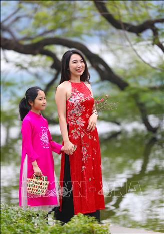 Du khách với tà áo dài thướt tha dạo hồ Gươm trong tiết trời vào Xuân.Ảnh: Thanh Tùng - TTXVN  