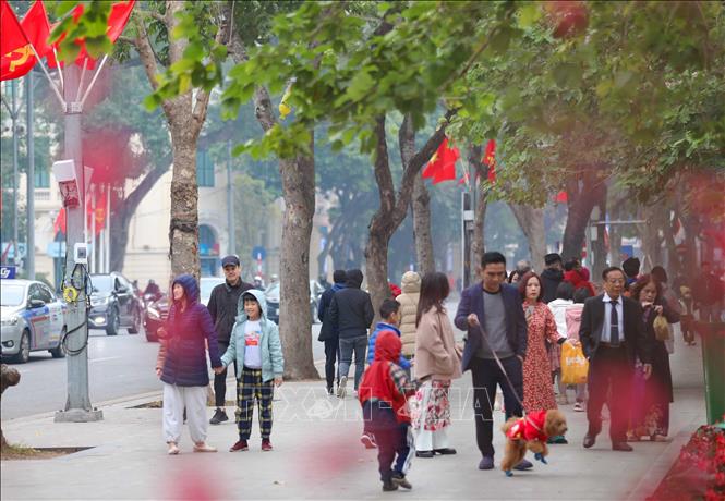 Người dân Thủ đô cùng du khách tới hồ Gươm để tản bộ, ngắm cảnh, chụp ảnh lưu niệm, tận hưởng không khí rực rỡ, ấm áp của mùa Xuân đang về. Ảnh: Thanh Tùng - TTXVN 