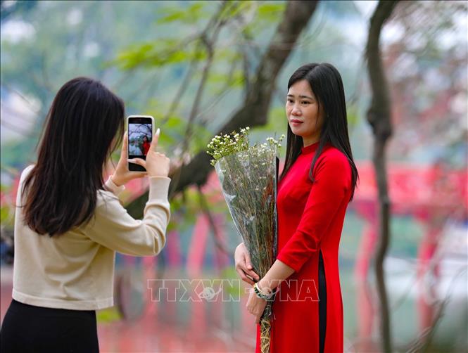 Cùng ngắm cảnh, chụp ảnh bên cầu Thê Húc dưới tiết trời vào Xuân. Ảnh: Thanh Tùng - TTXVN