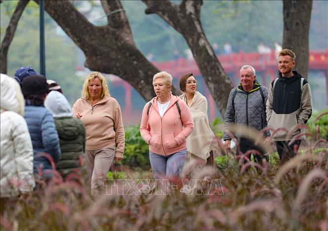 Người dân Thủ đô cùng du khách tới hồ Gươm để tản bộ, ngắm cảnh, chụp ảnh lưu niệm, tận hưởng không khí rực rỡ, ấm áp của mùa Xuân đang về. Ảnh: Thanh Tùng - TTXVN 