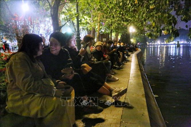 Trong ảnh:Đông người tập trung tại ven Hồ Gươm để chuẩn bị xem pháo hoa chào Xuân Quý Mão 2023. Ảnh: Tuấn Đức - TTXVN