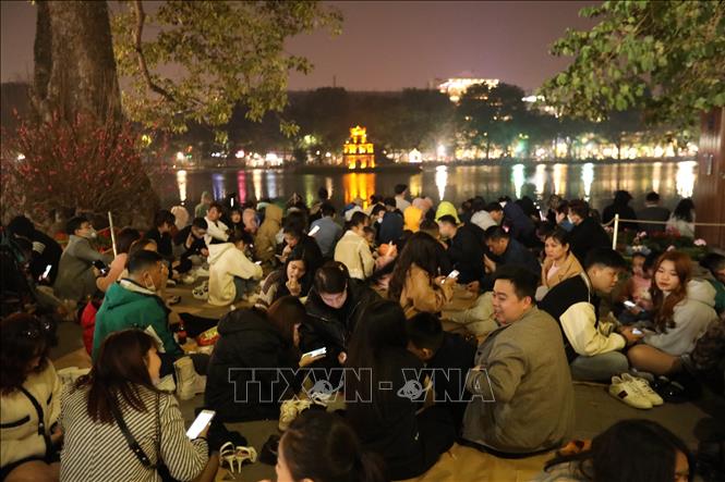 Trong ảnh: Ngay từ 11h, hàng ngàn người đã tập trung xung quanh khu vực Hồ Gươm chờ xem bắn pháo hoa đón năm mới. Ảnh: Hoàng Hiếu - TTXVN 