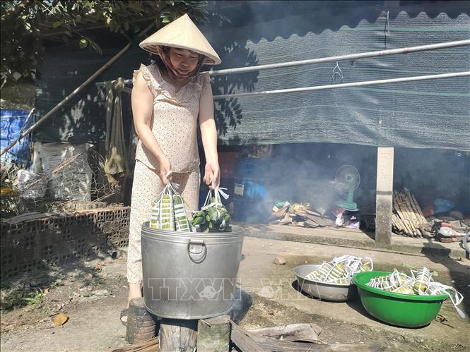 Các bà, các chị quây quần gói, nấu bánh tét để dâng lên tổ tiên. Ảnh: Huỳnh Phúc Hậu - TTXVN