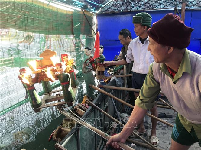 Các nghệ nhân chuẩn bị dụng cụ biểu diễn trong cánh gà sân khấu.  Ảnh: Tiến Vĩnh – TTXVN