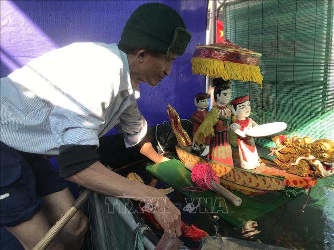 Nghệ nhân kiểm tra hoạt động của các con rối trước khi biểu diễn.  Ảnh: Tiến Vĩnh – TTXVN