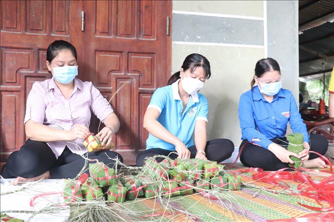 Các bà, các chị quây quần cùng nhau trò chuyện và dùng dây buộc bánh tét sau khi gói để mang đi luộc. Ảnh: Chương Đài - TTXVN
