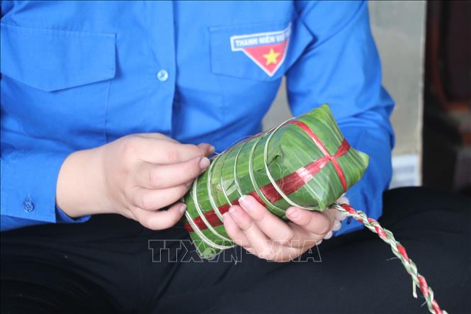 Bánh gói xong dùng dây lạt hoặc dây chuối (xé nhỏ đã phơi nắng cho héo, dai) quấn ngang thân đòn bánh từng sợi. Ảnh: Chương Đài - TTXVN