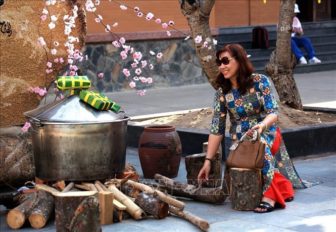 Trong ảnh: Du khách bên mô hình nấu bánh chưng ngày Tết trong khuôn viên chùa Hoằng Pháp. Ảnh: Hồng Đạt - TTXVN
