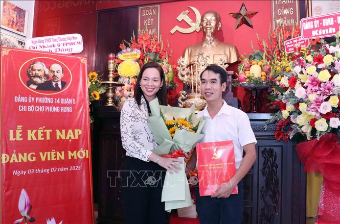 Trong ảnh: Bà Khương Lê Thuỳ Anh, Quận uỷ viên, Bí thư Đảng uỷ phường 14, quận 5, tặng hoa chúc mừng Đảng viên mới. Ảnh: Xuân Khu-TTXVN