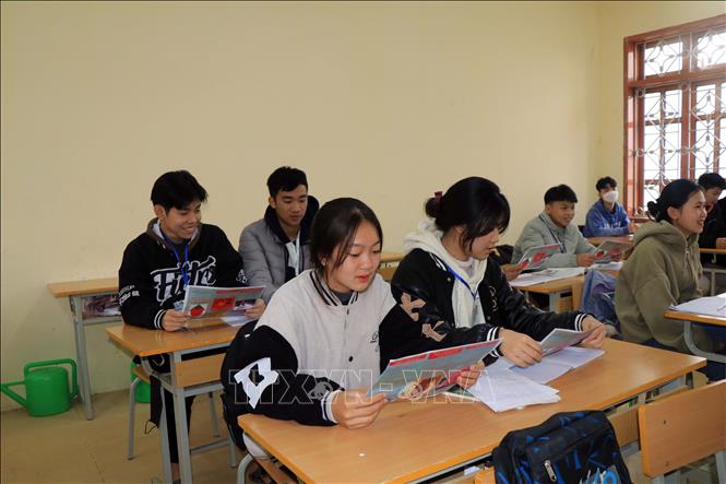 Các em học sinh tại huyện Vân Hồ tìm hiểu về tình trạng mất cân bằng tính khi sinh thông qua các tờ rơi tuyên truyền. Ảnh: Hữu Quyết - TTXVN