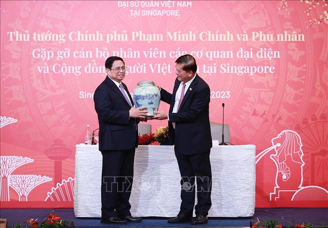 Thủ tướng Phạm Minh Chính tặng quà cho đại diện cán bộ, nhân viên các cơ quan đại diện Việt Nam tại Singapore. Ảnh: Dương Giang-TTXVN