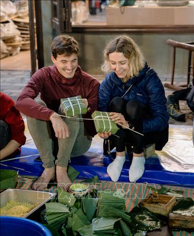 Trong ảnh: Du khách trải nghiệm gói bánh chưng. Ảnh: Thùy Dung - TTXVN