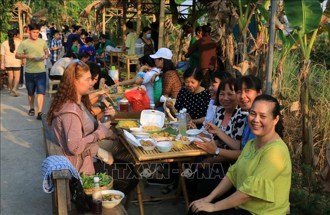 Du khách đến tham quan và thưởng thức nhiều món ăn đồng quê tại chợ quê cồn Tân Thuận Đông. Ảnh: Nhựt An - TTXVN