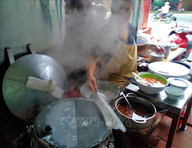 The cook spreads wet batter over the steaming basket into a thin sheet, adds minced pork and wood ear mushrooms, sometimes an egg, and then rolls the sheet to cover the fillings. VNA Photo: Phạm Hậu