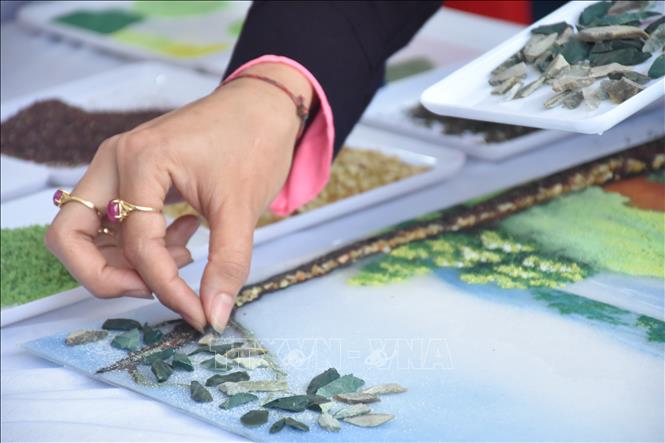 Trong ảnh: Nghệ nhân làm tranh đá quý tại phiên chợ. Ảnh: Tuấn Anh - TTXVN 
