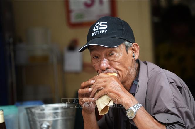 (Tư liệu) Người dân thưởng thức bánh mì tại một cửa hàng ở Hà Nội. Ảnh: AFP/ TTXVN
