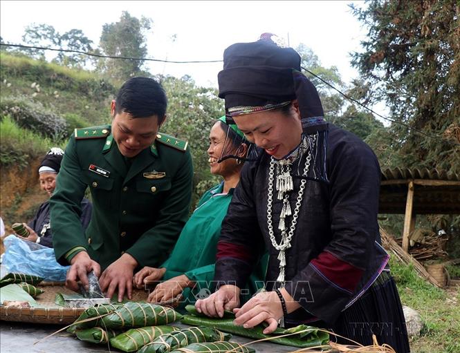 Cán bộ, chiến sĩ Đồn Biên phòng Simacai (Bộ đội Biên phòng tỉnh Lào Cai) tham gia gói bánh chưng với bà con dân tộc xã Nàn Sán, huyện Simacai trong Chương trình 