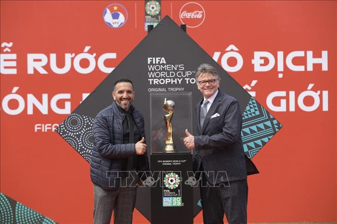 HLV trưởng Đội tuyển bóng đá nam Philippe Troussier và trợ lý chụp ảnh cùng chiếc Cúp vô địch Bóng đá nữ thế giới. Ảnh: Minh Quyết - TTXVN