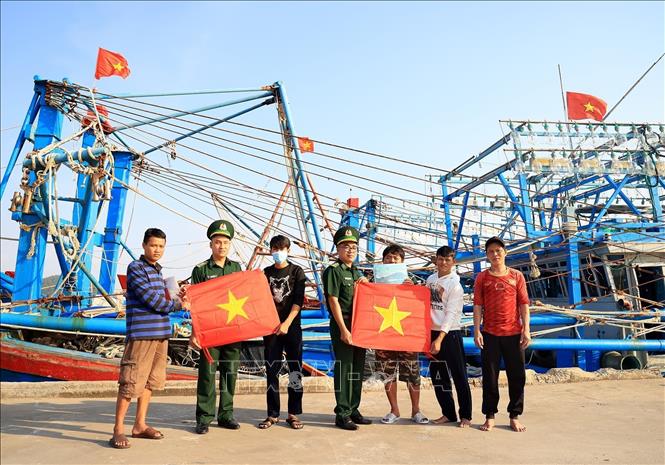 Cán bộ Trạm kiểm soát Biên phòng Pháo Đài, Đồn Biên phòng Cửa khẩu Quốc tế Hà Tiên (Kiên Giang) trao cờ Tổ quốc cho ngư dân. Ảnh: Hồng Đạt - TTXVN
