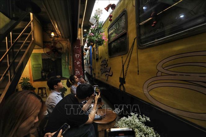 Du khách ngồi uống cafe ngay sát đường tàu khi tàu chạy qua (ảnh chụp chiều 4/3). Ảnh: Tuấn Anh - TTXVN